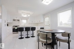 Modern kitchen featuring white cabinetry, a central island with seating, stainless steel appliances, and a tiled backsplash - 