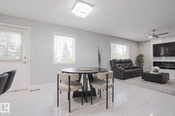 Open-concept living area featuring large format tile flooring and a modern ceiling fan - 
