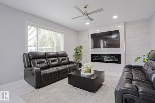 Living area with white wood-finish flooring, a contemporary ceiling fan, and recessed lighting - 313 Jillings Crescent, Edmonton, AB - Indoor Photo Showing Living Room With Fireplace