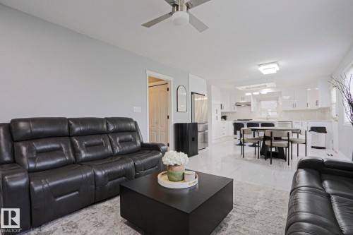 Open-concept living area featuring a ceiling fan with integrated lighting, sleek white cabinetry, stainless steel appliances, and polished tile flooring - 313 Jillings Crescent, Edmonton, AB - Indoor Photo Showing Living Room