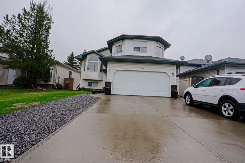 White siding residence featuring a two-car garage, concrete driveway, and a gravel landscaping strip - 313 Jillings Crescent, Edmonton, AB - Outdoor With Facade