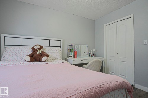 Bedroom featuring neutral wall colors, a textured ceiling, a white paneled headboard, and bi-fold closet doors - 313 Jillings Crescent, Edmonton, AB - Indoor Photo Showing Bedroom