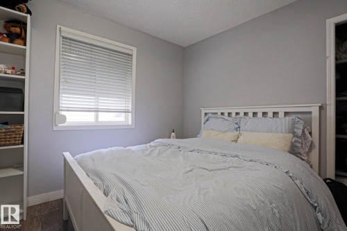 Well-lit room featuring light gray walls, a window with blinds, wood-finish flooring, and built-in white shelving - 313 Jillings Crescent, Edmonton, AB - Indoor Photo Showing Bedroom