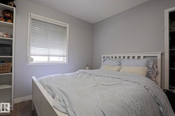 Well-lit room featuring light gray walls, a window with blinds, wood-finish flooring, and built-in white shelving - 