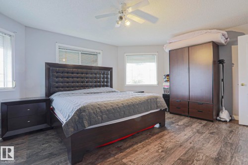 Spacious room featuring wood-finish flooring, two windows with blinds, a ceiling fan with integrated lighting, and light-toned walls - 313 Jillings Crescent, Edmonton, AB - Indoor Photo Showing Bedroom