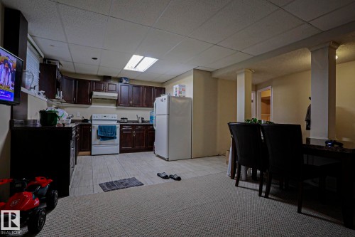 Kitchen area featuring dark wood-finish cabinetry, white appliances, and a tiled floor - 313 Jillings Crescent, Edmonton, AB - Indoor