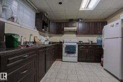 Kitchen featuring dark wood-finish cabinetry, solid surface countertops, a white electric range, and a white refrigerator - 