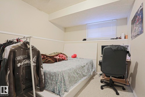 Carpeted room featuring a white bed frame, baseboard trim, and a window with horizontal blinds - 313 Jillings Crescent, Edmonton, AB - Indoor Photo Showing Bedroom