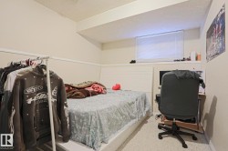 Carpeted room featuring a white bed frame, baseboard trim, and a window with horizontal blinds - 