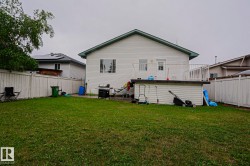 Expansive backyard with a manicured lawn, full perimeter privacy fencing, and a raised exterior deck - 