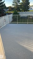Expansive deck featuring a textured light gray surface and white metal railing - 