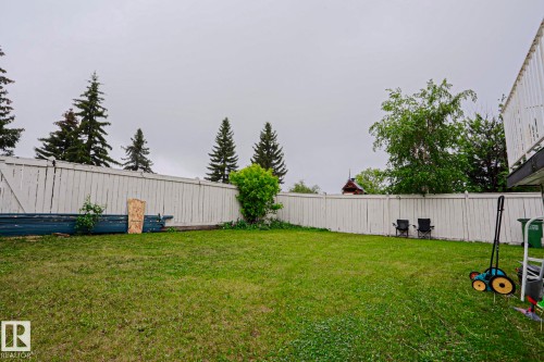 Expansive backyard featuring a lush green lawn, mature perimeter trees, and a white privacy fence - 313 Jillings Crescent, Edmonton, AB - Outdoor