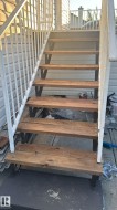 Exterior staircase featuring wood plank treads and white metal railings - 