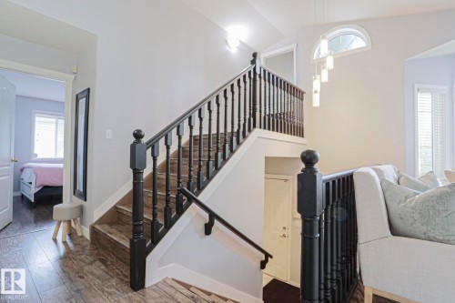 Wood-finish flooring throughout, complemented by a dark wood staircase with white risers and balusters - 313 Jillings Crescent, Edmonton, AB - Indoor Photo Showing Other Room