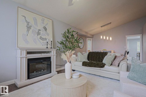 Living area featuring a detailed fireplace surround with an electric insert, vaulted ceilings, and wood-finish flooring - 313 Jillings Crescent, Edmonton, AB - Indoor Photo Showing Living Room With Fireplace