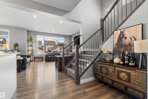Open-concept living area featuring wood-finish flooring, recessed lighting, a modern staircase with carpeted treads and metal balusters, and a built-in wall niche - 524 Mcdonough Way, Edmonton, AB - Indoor Photo Showing Other Room