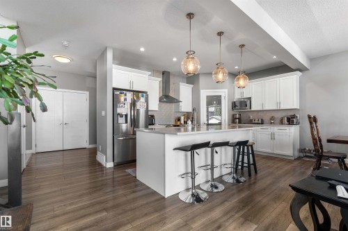 Contemporary kitchen featuring an island with seating, white shaker-style cabinetry, stainless steel appliances, and pendant lighting - 524 Mcdonough Way, Edmonton, AB - Indoor Photo Showing Kitchen With Stainless Steel Kitchen With Upgraded Kitchen