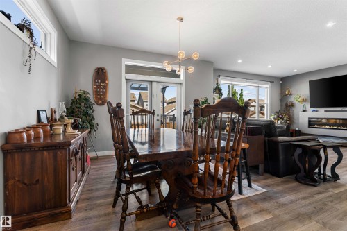 Open-concept living area featuring wood-finish flooring, a contemporary linear fireplace, and modern light fixtures - 524 Mcdonough Way, Edmonton, AB - Indoor Photo Showing Dining Room