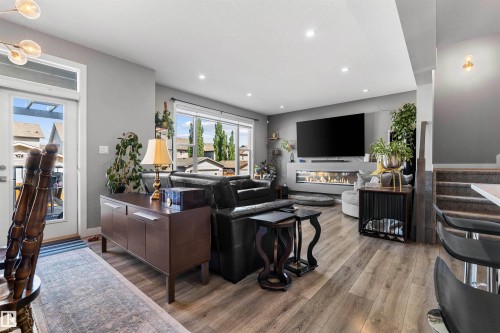 Spacious living area featuring wood-finish flooring, recessed lighting, and a linear fireplace - 524 Mcdonough Way, Edmonton, AB - Indoor