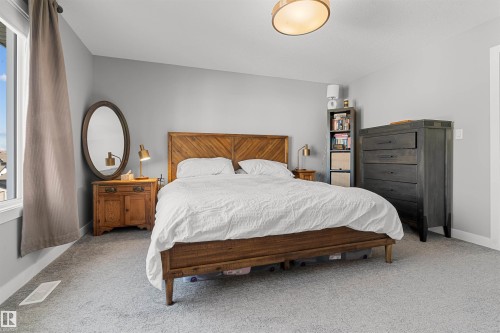 Bedroom featuring light gray walls, plush gray carpeting, a large window, and a modern ceiling light fixture - 524 Mcdonough Way, Edmonton, AB - Indoor Photo Showing Bedroom