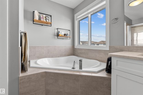 Soaking tub with a polished chrome faucet, surrounded by large format tile - 524 Mcdonough Way, Edmonton, AB - Indoor Photo Showing Bathroom