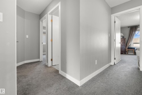 Interior hallway featuring neutral gray walls, light gray carpeting, white trim, and white paneled doors with bronze hinges - 524 Mcdonough Way, Edmonton, AB - Indoor Photo Showing Other Room