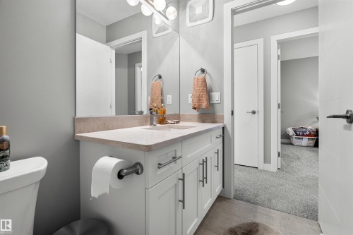 Bathroom featuring a single vanity with a stone countertop, an undermount sink, and a large mirror - 524 Mcdonough Way, Edmonton, AB - Indoor Photo Showing Bathroom