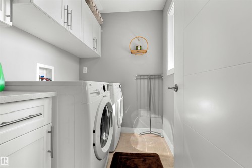 Contemporary laundry room featuring white cabinetry with silver-tone hardware, a light-toned countertop, and light wood-finish flooring - 524 Mcdonough Way, Edmonton, AB - Indoor Photo Showing Laundry Room