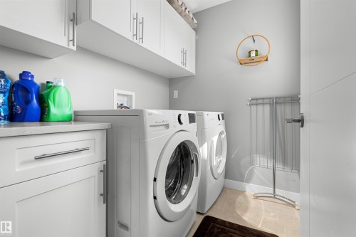 Laundry area featuring white cabinetry with brushed nickel hardware, a light-toned countertop, and integrated appliance hookups - 524 Mcdonough Way, Edmonton, AB - Indoor Photo Showing Laundry Room