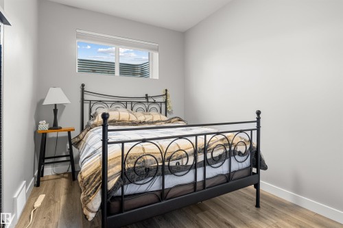 Light-filled room featuring wood-finish flooring, a window with horizontal blinds, and neutral wall paint - 524 Mcdonough Way, Edmonton, AB - Indoor Photo Showing Bedroom