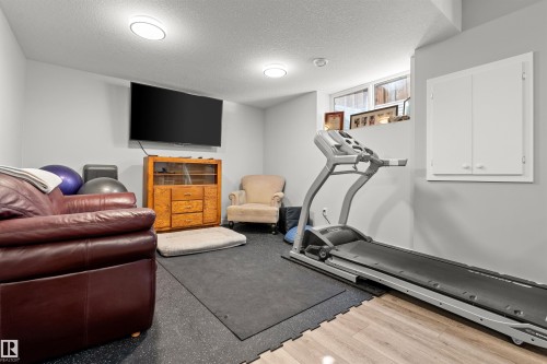 Recreation room with mixed flooring featuring wood-finish planks and interlocking rubber mats - 524 Mcdonough Way, Edmonton, AB - Indoor Photo Showing Gym Room