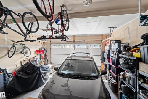 Attached two-car garage featuring a white overhead door with upper window panels, light tan wall paneling, and a ceiling-mounted light fixture - 524 Mcdonough Way, Edmonton, AB - Indoor Photo Showing Garage