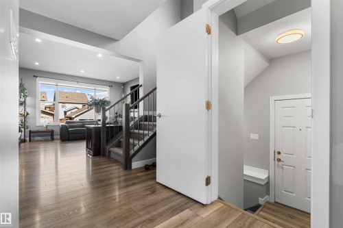 Open concept entryway with wood-finish flooring, recessed lighting, and a contemporary staircase with carpeted treads and dark wood banister - 524 Mcdonough Way, Edmonton, AB - Indoor Photo Showing Other Room