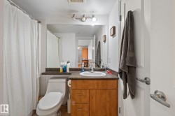 Full bathroom with a wood-finish vanity, integrated sink, and dark countertop - 