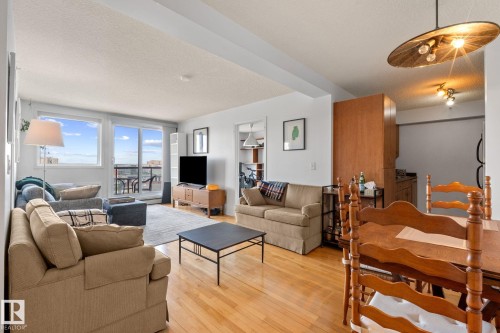Open-concept living space featuring wood-finish flooring, a wall of windows, and a sliding glass door providing access to an outdoor patio - 905 10303 105 Street Nw, Edmonton, AB - Indoor Photo Showing Living Room