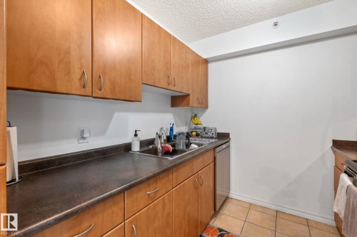 Kitchen featuring light wood-finish cabinetry, dark countertops, and a stainless steel dishwasher - 905 10303 105 Street Nw, Edmonton, AB - Indoor