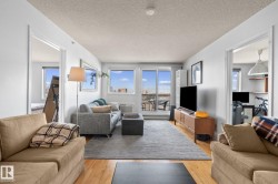 Living area featuring wood-finish flooring, a neutral color palette, and large windows with cityscape scenery - 