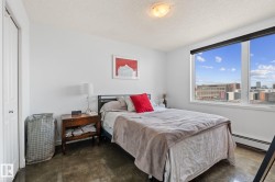 Spacious room with large windows offering urban scenery, textured flooring, and a built-in closet with a white panel door - 