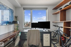 Dedicated office space featuring large windows, wood-finish flooring, a built-in wood shelving unit, and a long wood-finish console table - 