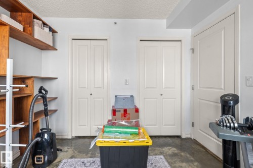 Utility space featuring wood-finish shelving, multiple bi-fold closet doors, and a paneled entry door - 905 10303 105 Street Nw, Edmonton, AB - Indoor