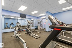 Fitness center featuring multiple exercise machines, mirrored wall, rubber flooring, and recessed lighting - 