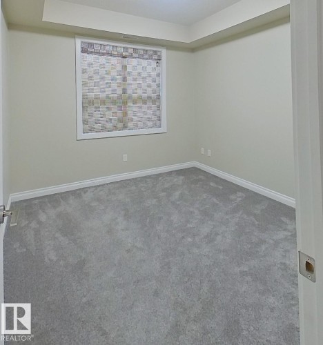 Spacious room featuring light gray carpeting, neutral-toned walls, and a recessed ceiling design - 108 9603 98 Avenue Nw, Edmonton, AB - Indoor Photo Showing Other Room