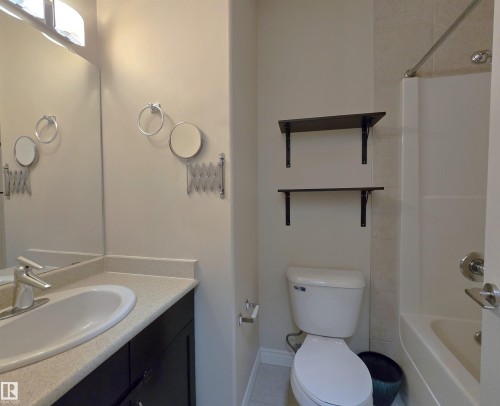 Bathroom featuring a single vanity with an integrated sink, a light-toned countertop, and dark cabinetry - 108 9603 98 Avenue Nw, Edmonton, AB - Indoor Photo Showing Bathroom