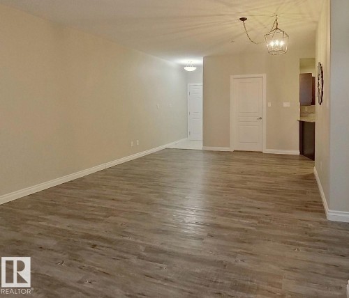 Spacious interior featuring wood-finish flooring, neutral wall tones, and white trim - 108 9603 98 Avenue Nw, Edmonton, AB - Indoor Photo Showing Other Room