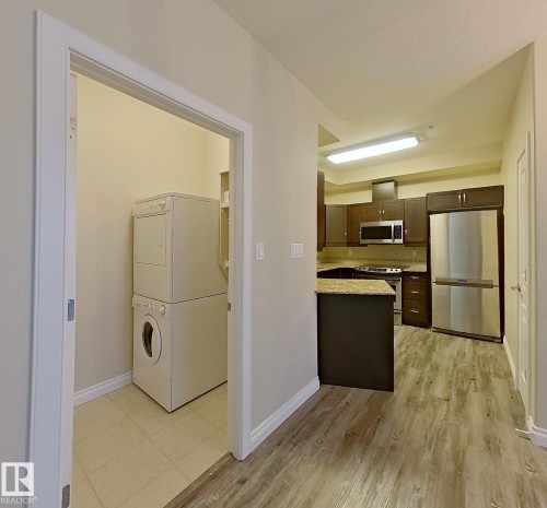 Dedicated laundry area with stacked appliances and tiled flooring - 108 9603 98 Avenue Nw, Edmonton, AB - Indoor