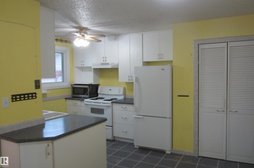 Kitchen featuring white cabinetry, dark countertops, a window, and slate-finish flooring - 3814 37 Avenue, Leduc, AB - Indoor Photo Showing Kitchen