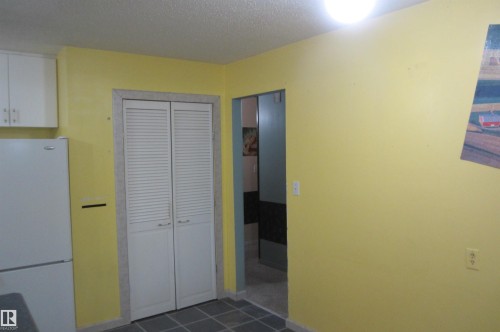 Kitchen featuring yellow walls, white cabinetry, a white refrigerator, and gray square floor tiles - 3814 37 Avenue, Leduc, AB - Indoor Photo Showing Other Room