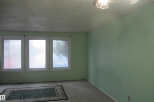 Room featuring three rectangular windows with white trim, light green walls, and carpet flooring - 3814 37 Avenue, Leduc, AB - Indoor Photo Showing Other Room