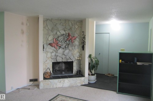 Floor-to-ceiling stone fireplace with a black tile hearth and an integrated firebox - 3814 37 Avenue, Leduc, AB - Indoor Photo Showing Other Room With Fireplace