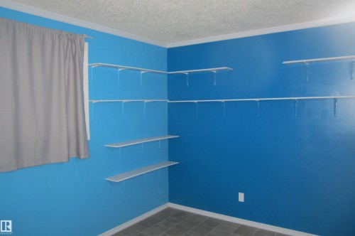 Room featuring an array of white wall-mounted shelving, a window with trim, crown molding, and tiled flooring - 3814 37 Avenue, Leduc, AB - Indoor Photo Showing Other Room